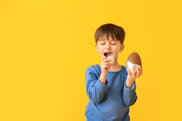 Poster - Cute little boy with chocolate Easter eggs on color background