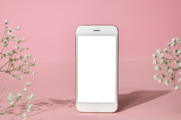 mobile phone mock up and white flowers on pink background.spring pastel colour, hard shadows