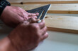 Carpenter marking a pine wood board with a speed square on white working bench.