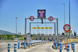 Light traffic in the toll plaza under the blue sky with multiple highway signs, electronic toll collection.