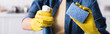 Cropped view of woman in rubber gloves holding detergent and blurred sponge, banner