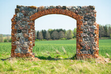 Old Stone And Brick Stone House Entrance Arch In A Green Grain Rapeseed Field With A Blue Sky.