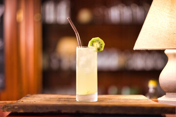 drink closeup with bar background standing on wooden plate with lamp on the left