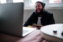 Mature Man With Laptop Laughing At Home