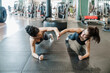 © Eva Blanco/Westend61 - Female athlete friends giving high-five while doing plank in health studio