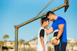 © Miguel Frias/Westend61 - Smiling father and son touching forehead while standing at sports court