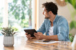© steve brookland/Westend61 - Male freelancer day dreaming while holding digital tablet at home office