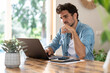 © steve brookland/Westend61 - Concentrated male freelancer holding eyeglasses while working on laptop at table