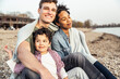© Uwe Umst√§tter/Westend61 - Smiling man sitting with family covered in blanket over pebble