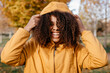 © Tania Cervi√°n/Westend61 - Cheerful Afro woman holding jacket hood in park during autumn