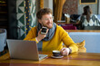 © Vasily Pindyurin/Westend61 - Male entrepreneur with laptop sending voice message through mobile phone while having coffee at cafe