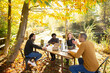 © Martin Barraud/Caia Image - Business people eating and meeting at table in sunny autumn park