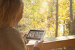 © Martin Barraud/Caia Image - Woman video chatting with friends on digital tablet at autumn window