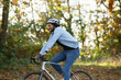 © Martin Barraud/Caia Image - Happy young man riding bicycle in autumn park