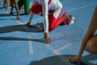 © Trevor Adeline/Caia Image - Female track and field athletes at starting line on blue track