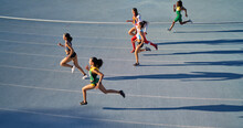 Female Track And Field Athletes Running In Competition On Blue Track