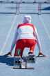 © Trevor Adeline/Caia Image - Female track and field athlete in hijab at starting block on track