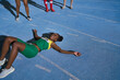 © Trevor Adeline/Caia Image - Tired track and field athlete laying on sunny track
