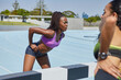 © Trevor Adeline/Caia Image - Female track and field athletes stretching on sunny track