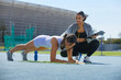 © Trevor Adeline/Caia Image - Trainer helping female track and field athlete doing planks on track