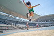 © Trevor Adeline/Caia Image - Female track and field athlete long jumping over sand