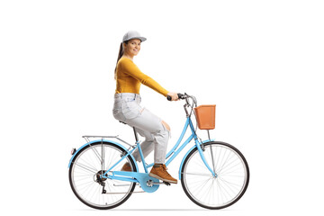 Sticker - Full length profile shot of a young female riding a city bicycle and looking at camera