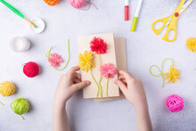 Small Child Doing A Bouquet Of Flowers Out Of Coloured Paper And Coloured Knitting Balls For Mom. Simple Gift Idea. View Top, Copy Space