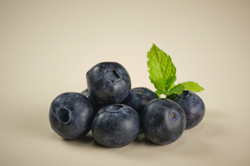 Wall Mural - Blueberries isolated on cream background and with green leaves in the background