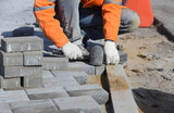 Fototapeta  - A worker levels the paving slabs with a hammer.