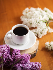 Wall Mural - A cup of coffee on a wooden table, blooming lilac