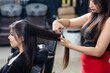 A hair dresser provides hair styling services to a pretty young Indian woman, beautiful woman gets her hair done at a salon.