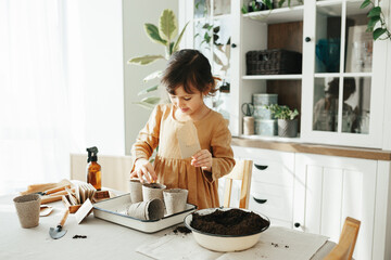 6 years old girl planting herbs at home