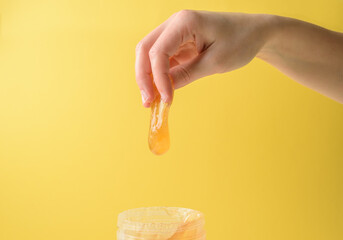 Wall Mural - Hand with sugar wax piece from jar on yellow