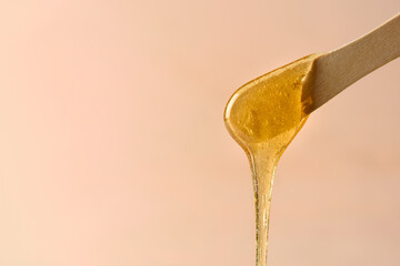 Liquid yellow sugar paste or wax for epilation on wooden stick or spatula closeup