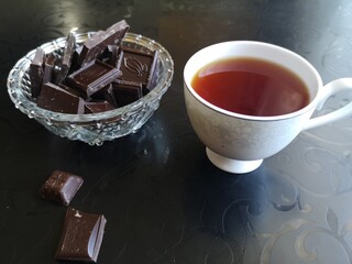 Cup of tea with chocolate on a black table