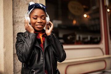 Young african woman outdoors. Beautiful woman listening to music while walking through the city..