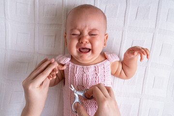 crying newborn baby cries while cutting nails, horizontal photo