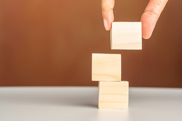 Close-up of hand holding empty wooden block on white table with a vintage background. Space for text