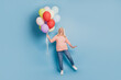 Photo of charming old woman hold many air baloons in pink jumper on blue background