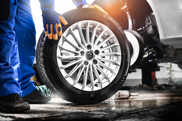 Poster - Auto mechanic working in garage and changing wheel alloy tire.