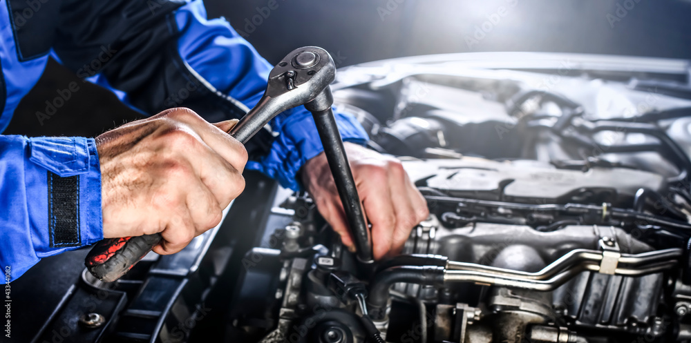 Auto mechanic working on car broken engine in mechanics service or garage.