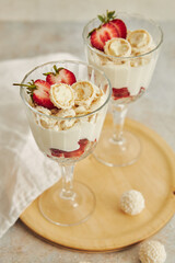 Sticker - Delicious cream dessert with coconut truffles and strawberries on a wooden round serving board