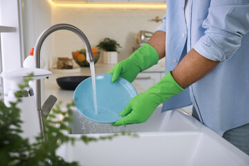 Wall Mural - Man washing plate above sink in kitchen, closeup