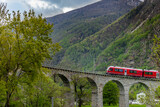 Fototapeta Most - The red train on the circular viaduct bridge near Brusio on the Swiss Alps in Spring