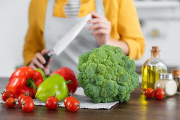 ripe vegetables near woman with knife on blurred background