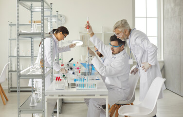 Professional medical scientist group working in modern chemistry laboratory. Health care researchers preparing and analyzing test samples under senior supervisor control. Research lab concept