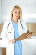 © Iryna - Woman-doctor standing in hospital or clinic and filling up medication history record form. Data and best service in medicine and healthcare