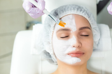 Wall Mural - Facial skin care and protection. A young woman at a beauticians appointment. The specialist applies a cream mask to the face