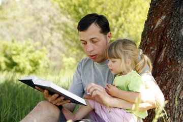 Canvas Print - happy father with a child reading a book on the nature of the Bible