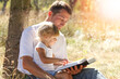© Kostia - Happy parents with a child read the Bible in the nature park